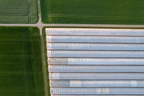 an aerial view of a green field and a white building