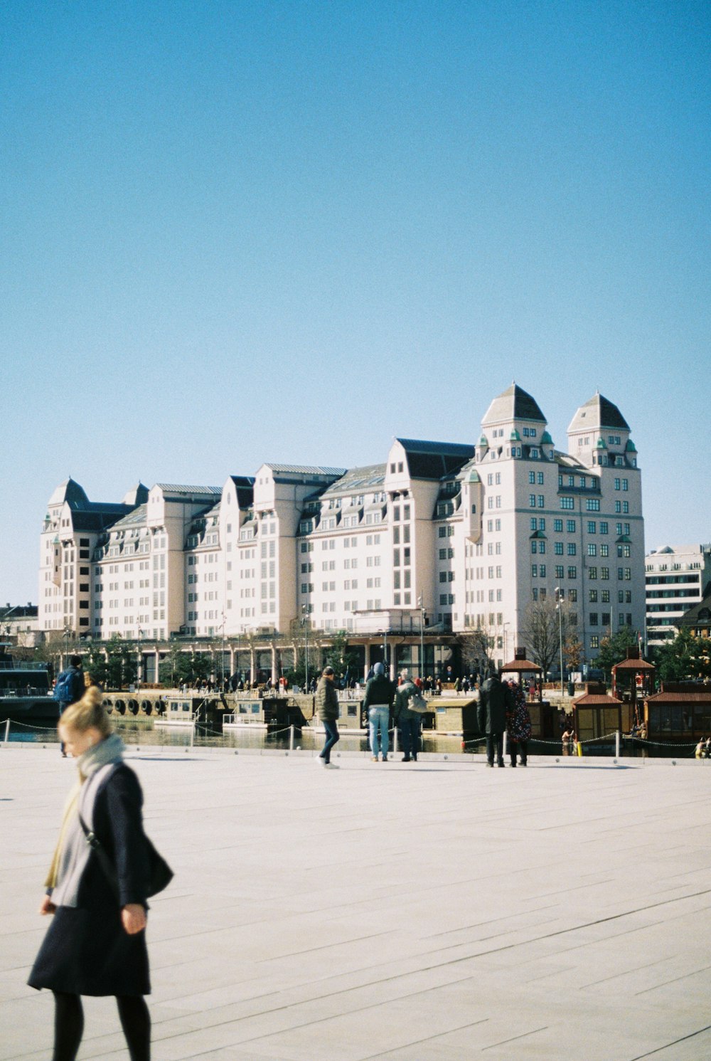 a woman walking down a sidewalk in front of a large building