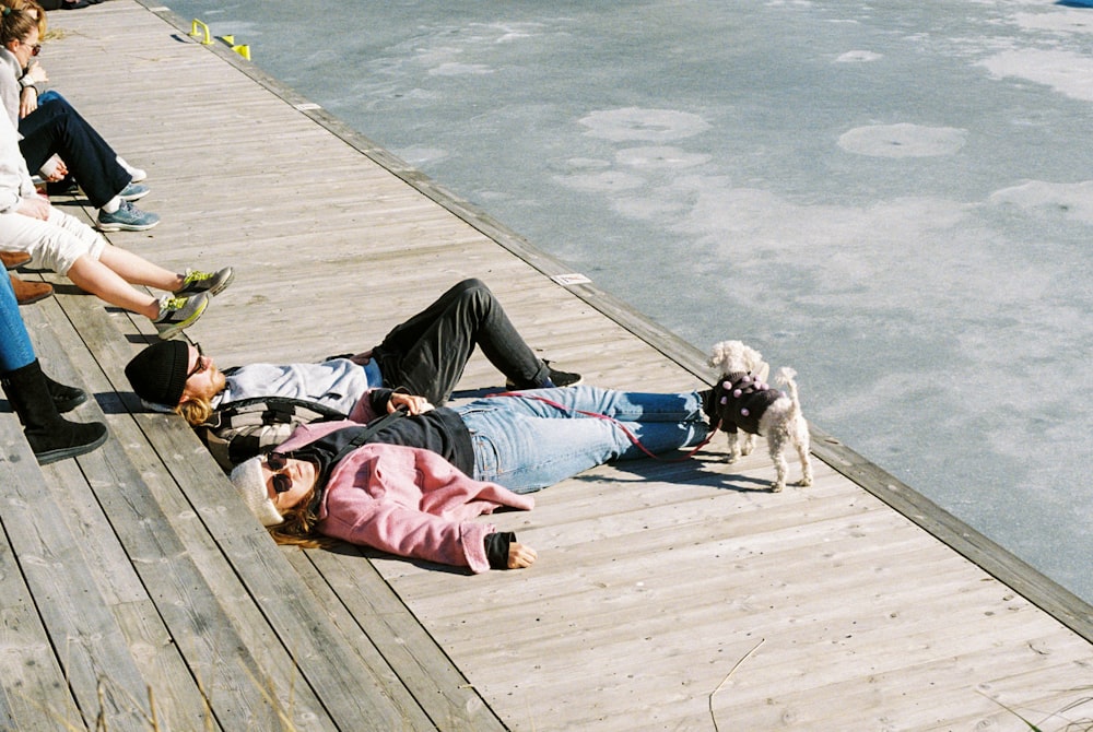 a group of people sitting on a dock next to a dog