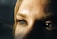 A close-up of a person's eyes, showcasing detailed eyelashes and eyebrows. The lighting casts shadows, creating a dramatic effect on the skin texture.