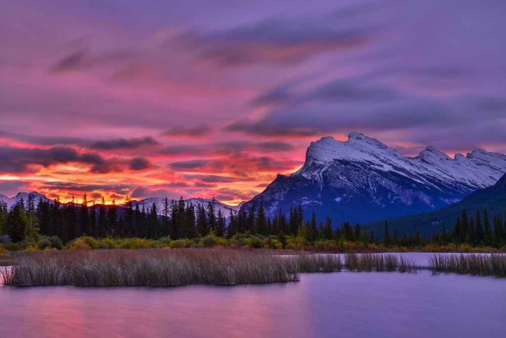 a beautiful sunset over a mountain range with a lake in the foreground
