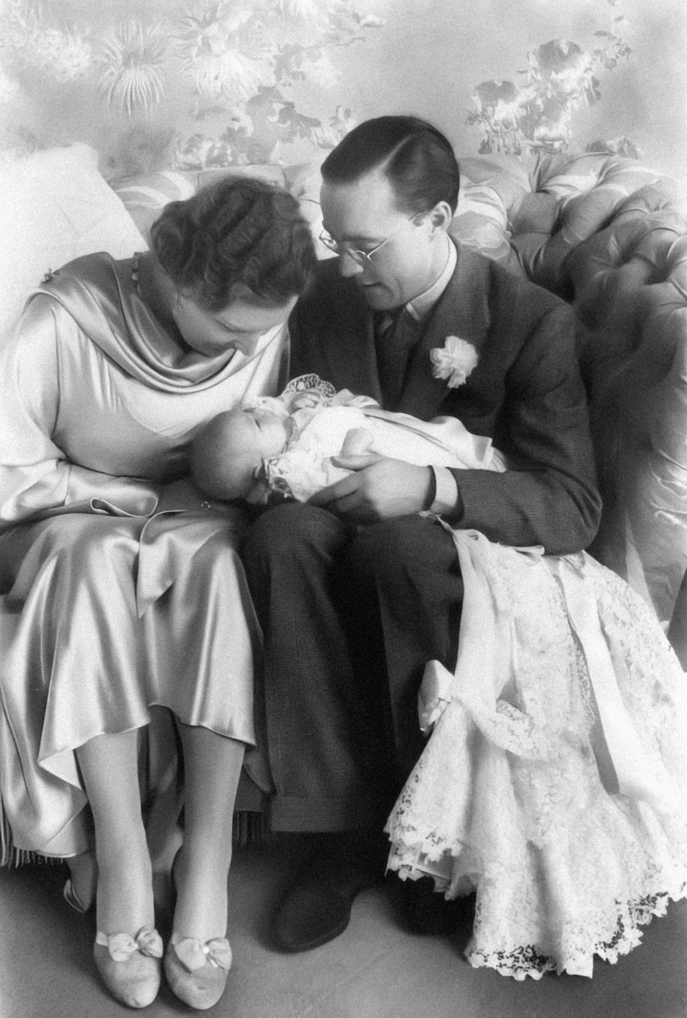 a black and white photo of a man and woman holding a baby