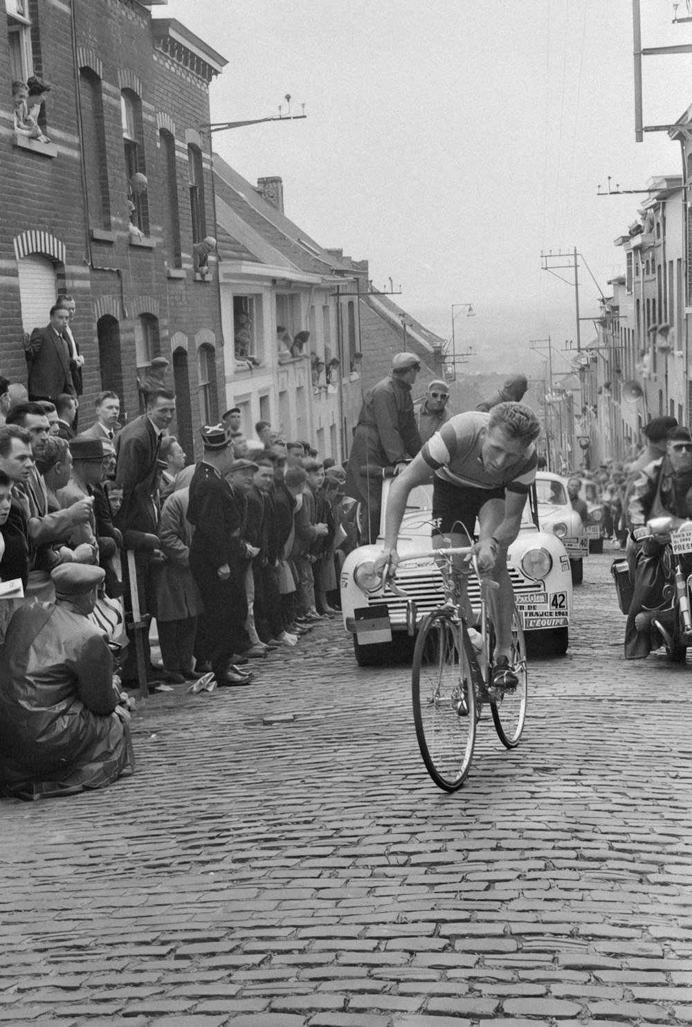 a man riding a bike down a street next to a crowd of people