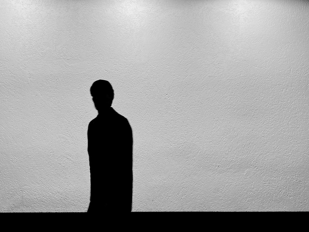 a black and white photo of a man standing in front of a wall