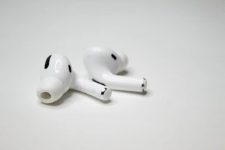 Sleek pair of wireless earbuds resting on a smooth, minimalist black surface with soft glowing light accents.