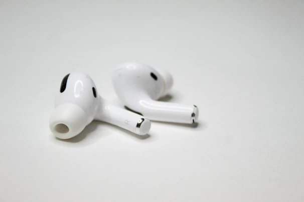 Sleek black wireless earbuds with neon purple accents resting on a reflective surface.