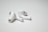 A pair of wireless earbuds resting on a flat, white surface. The earbuds have a sleek design with a glossy finish, featuring small black accents and an ergonomic shape.