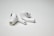 A pair of wireless earbuds resting on a flat, white surface. The earbuds have a sleek design with a glossy finish, featuring small black accents and an ergonomic shape.