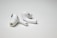 A pair of wireless earbuds resting on a flat, white surface. The earbuds have a sleek design with a glossy finish, featuring small black accents and an ergonomic shape.