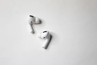 Modern wireless earbuds resting on a minimalist white surface.