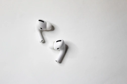 Modern wireless earbuds resting on a minimalist white surface.