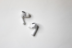 A sleek wireless earbud set resting on a minimalist white surface.