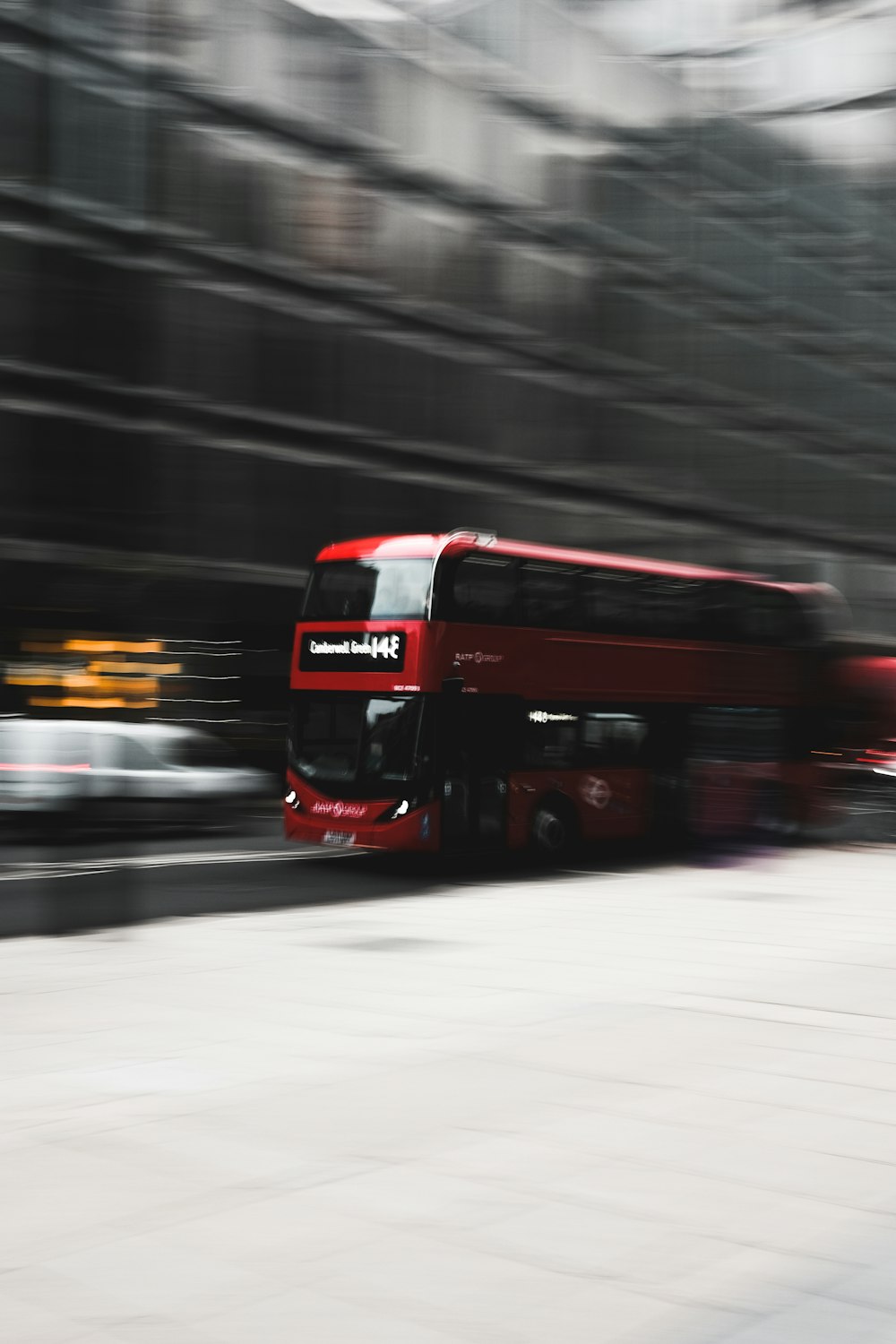 Ein roter Bus, der eine Straße neben einem hohen Gebäude hinunterfährt