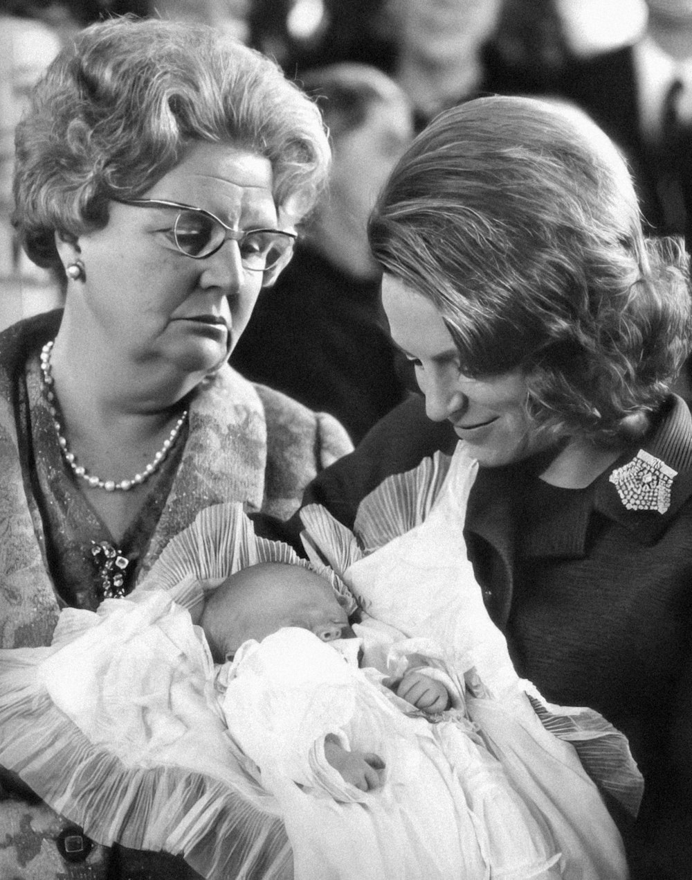 a black and white photo of two women holding a baby