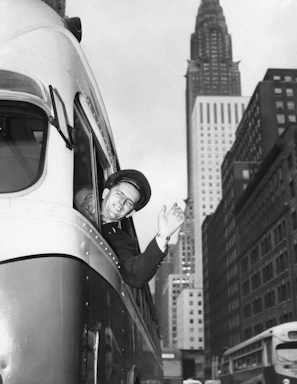 A driver in uniform standing proudly next to one of the company’s buses, smiling.