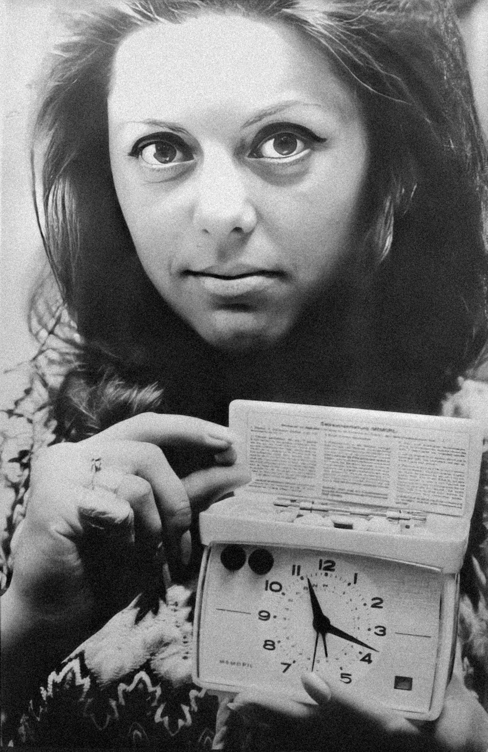 a black and white photo of a woman holding a clock