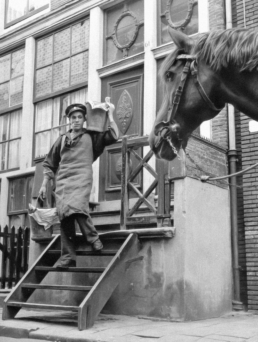 a black and white photo of a man standing next to a horse
