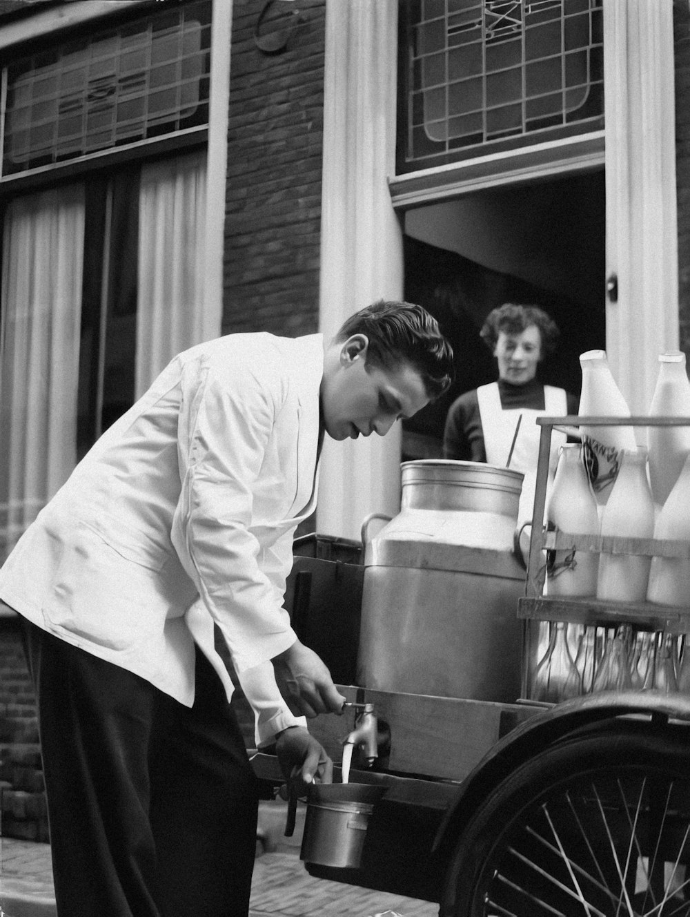 a man in a chef's coat is pouring milk from a jug into a