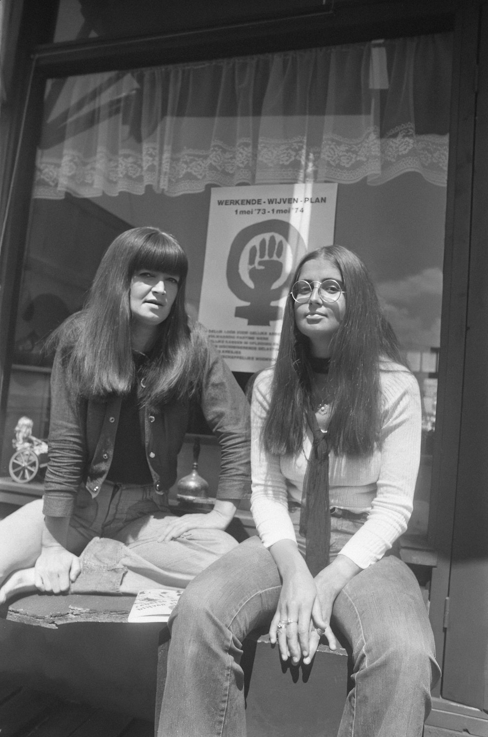 two women sitting on a bench in front of a store