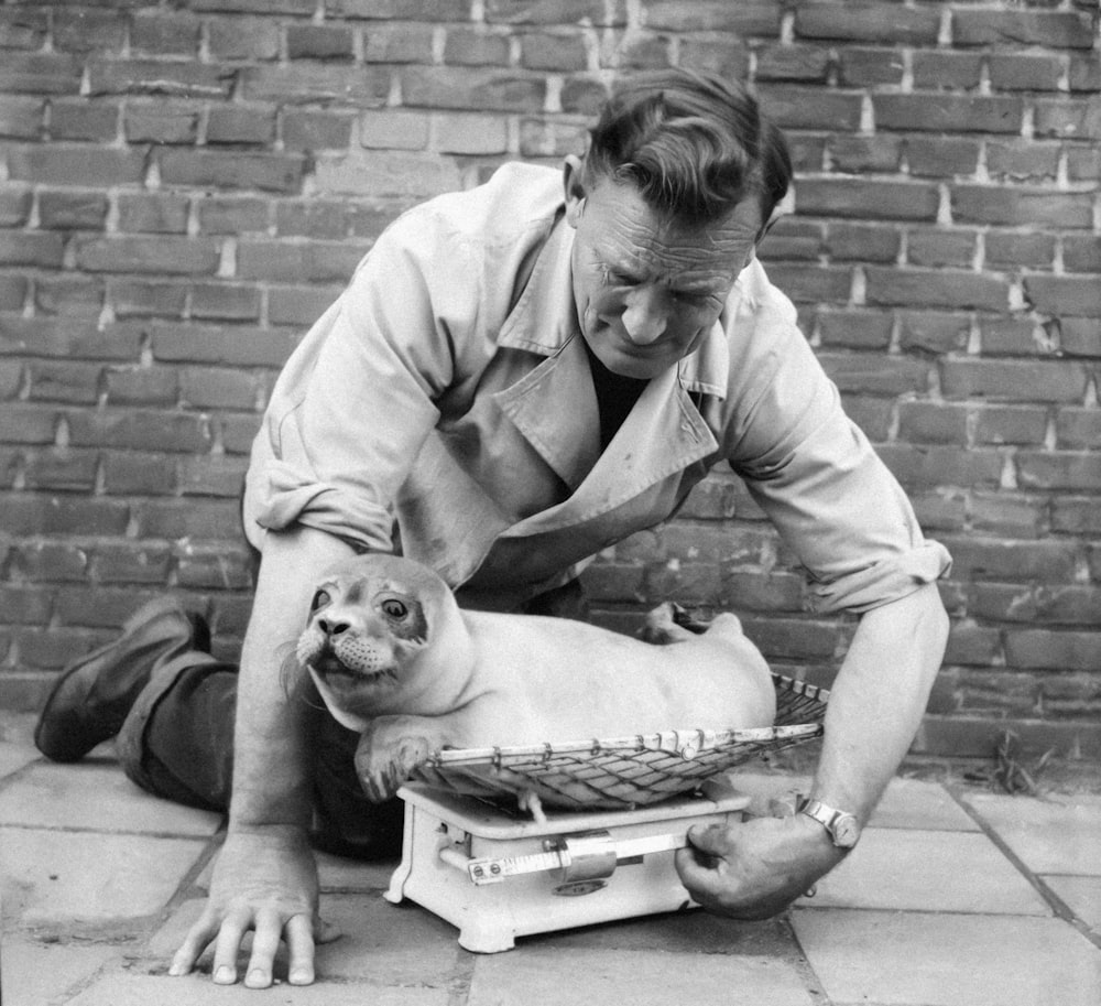 a man kneeling down next to a small dog