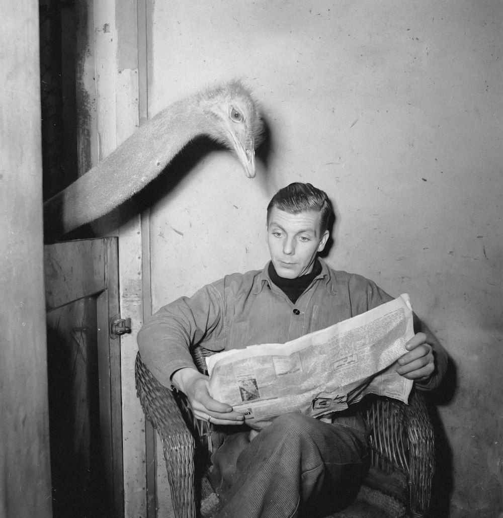 a man sitting in a chair with an ostrich on his head
