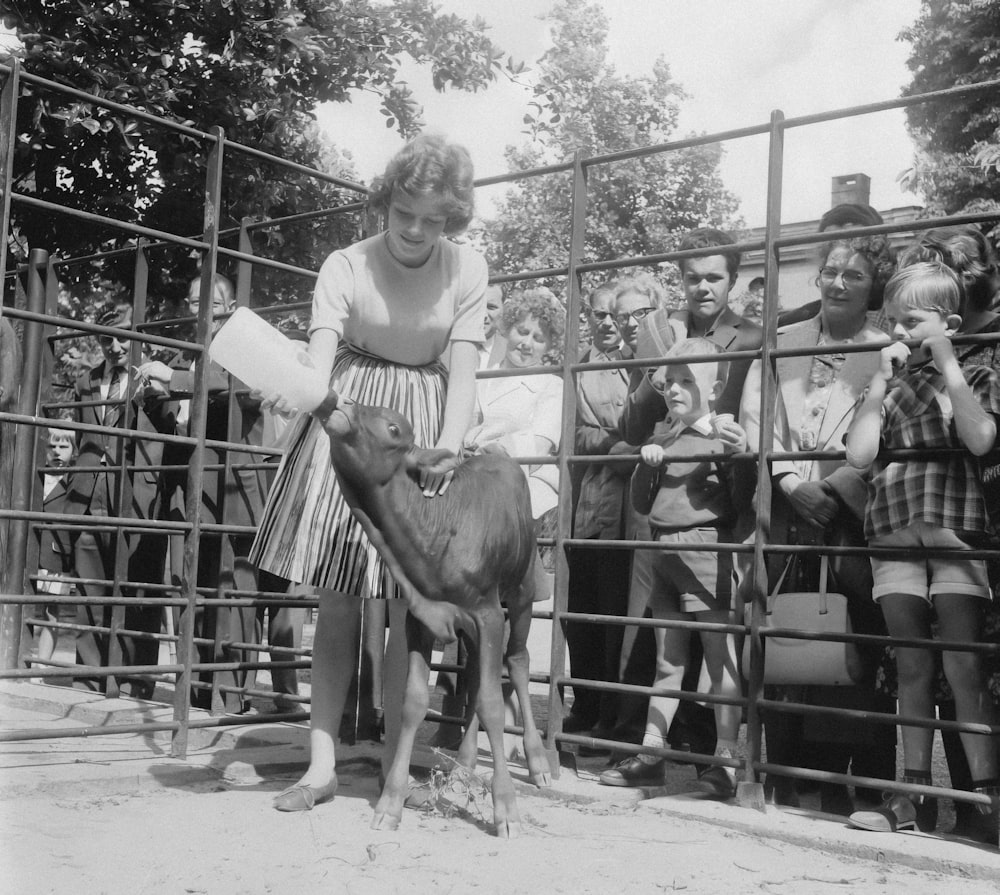 a woman standing next to a cow in front of a crowd of people