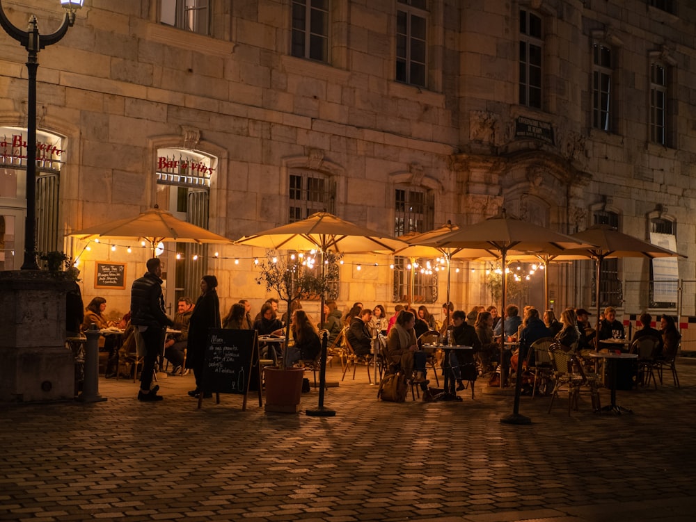 a group of people sitting at tables under umbrellas