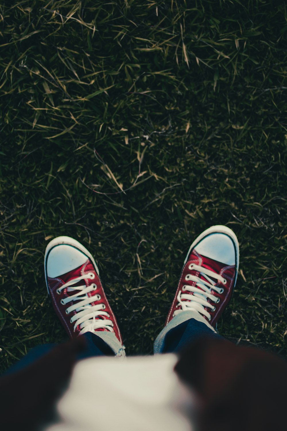 a person wearing red and white sneakers standing in the grass