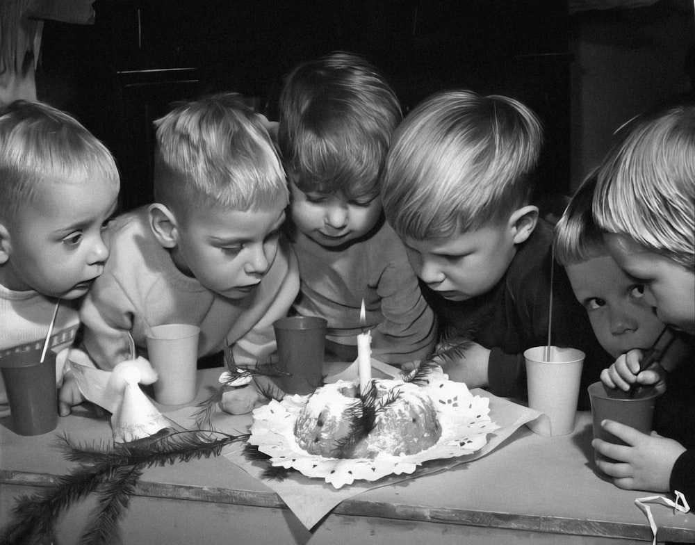 a group of children blowing out candles on a cake
