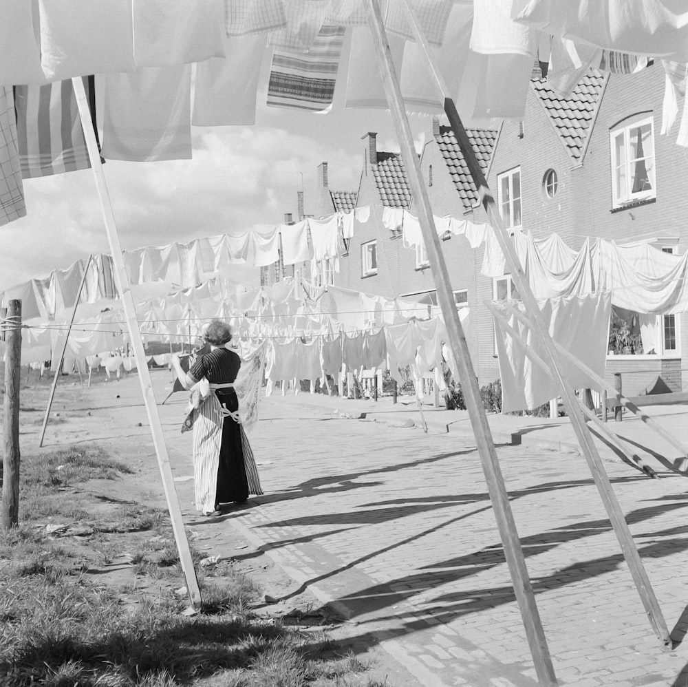 a black and white photo of a woman standing in front of a row of flags