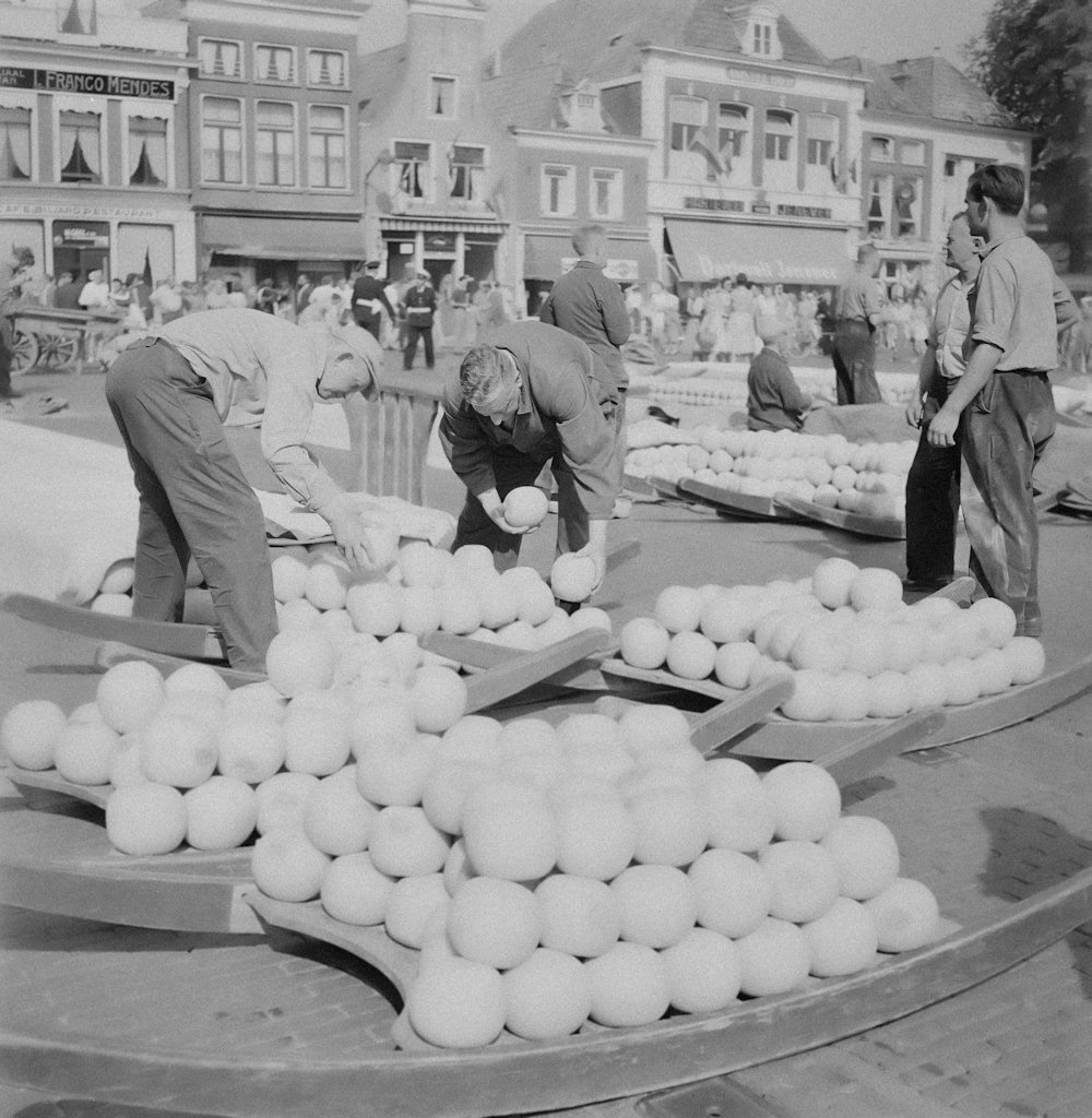 a black and white photo of people picking up produce