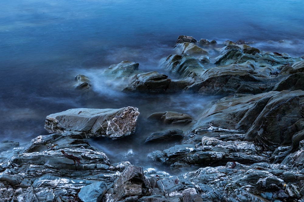 a rocky shore with a body of water in the background