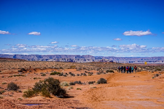A group of people walking through a desert landscape with historical landmarks.