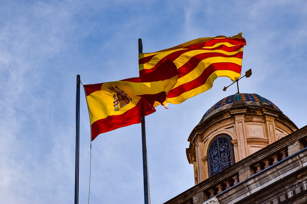 two flags flying next to each other in front of a building