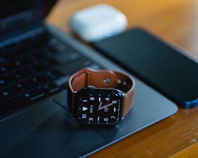 an apple watch sitting on top of a laptop computer