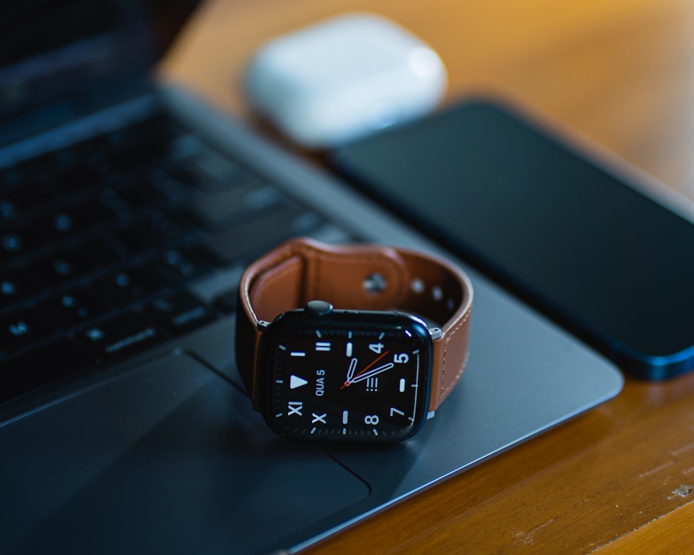 an apple watch sitting on top of a laptop computer