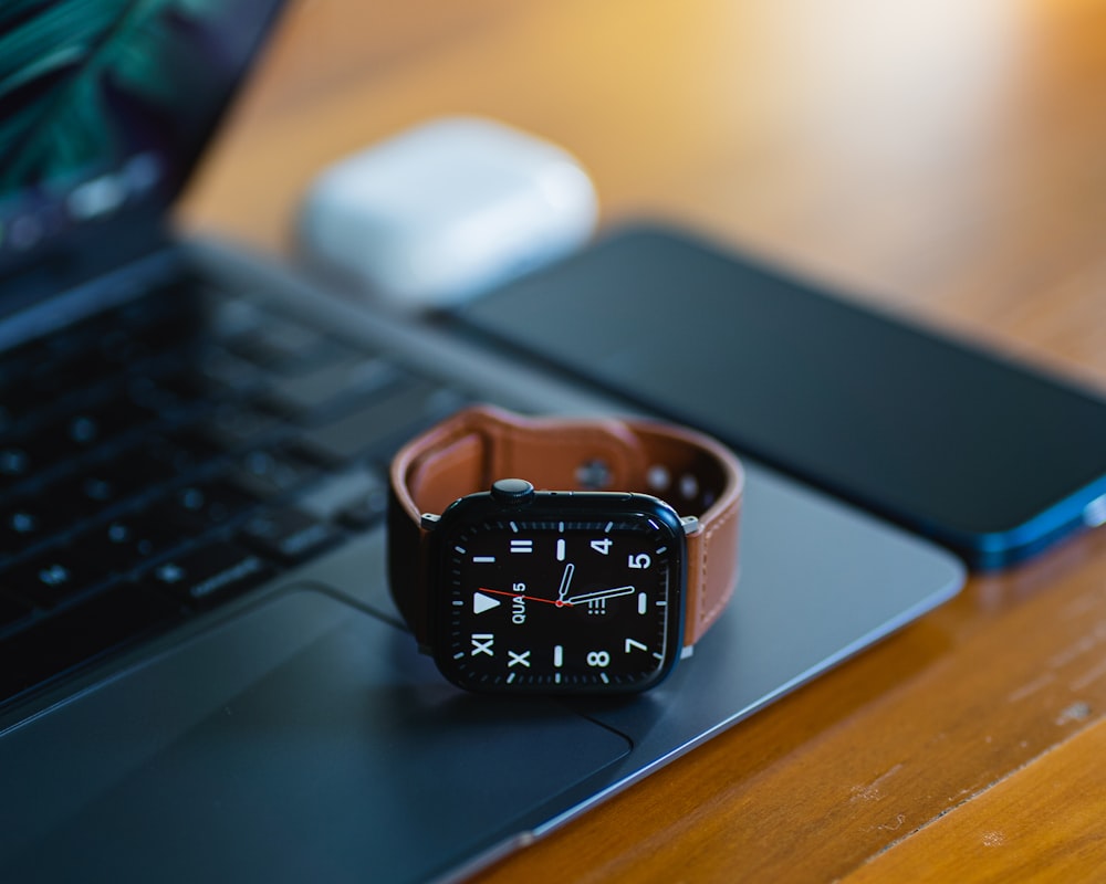 an apple watch sitting on top of a laptop computer