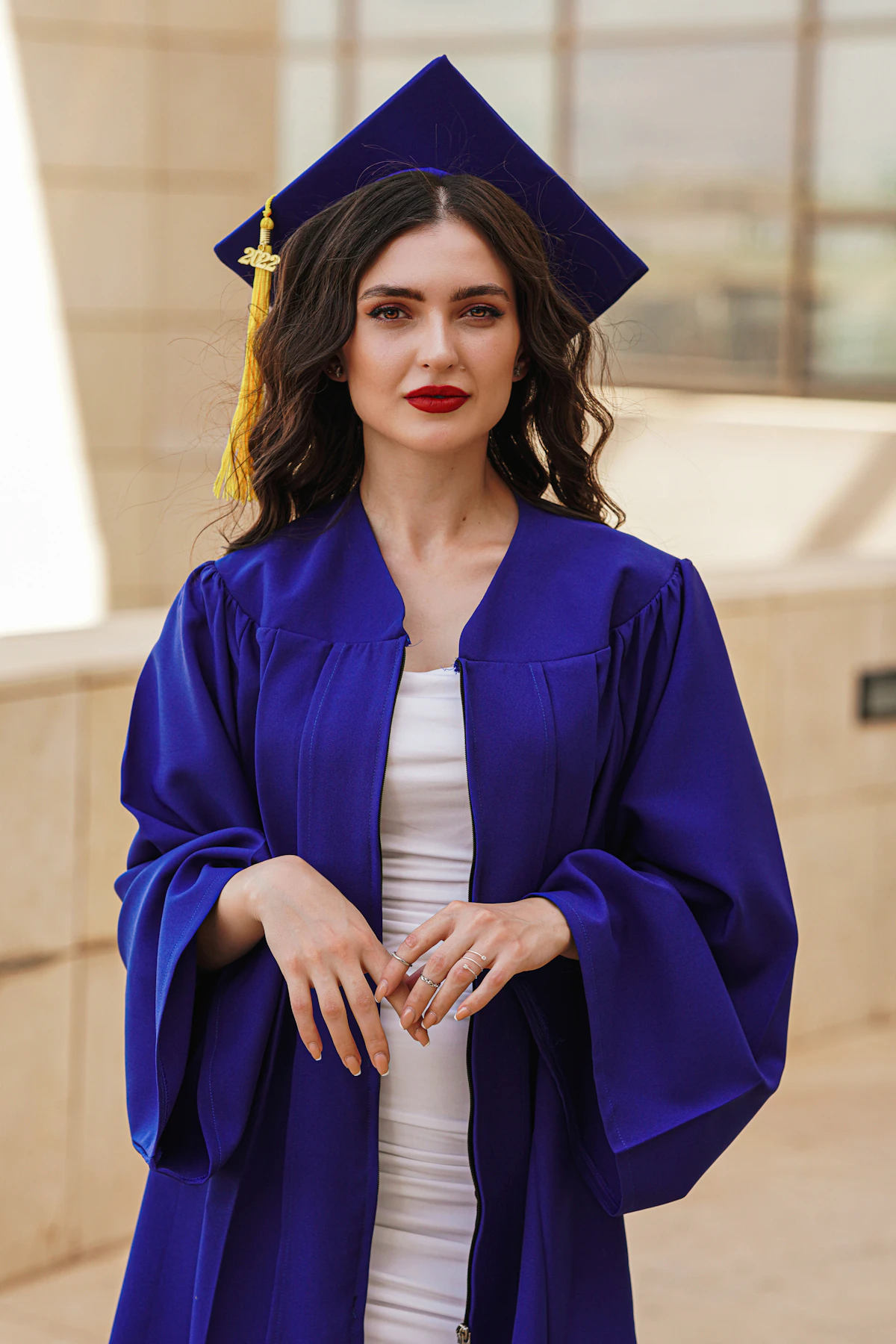 Young woman student smiling confidently in academic graduation gown holding diploma
