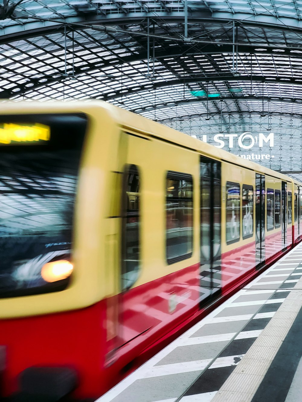 a yellow and red train traveling through a train station