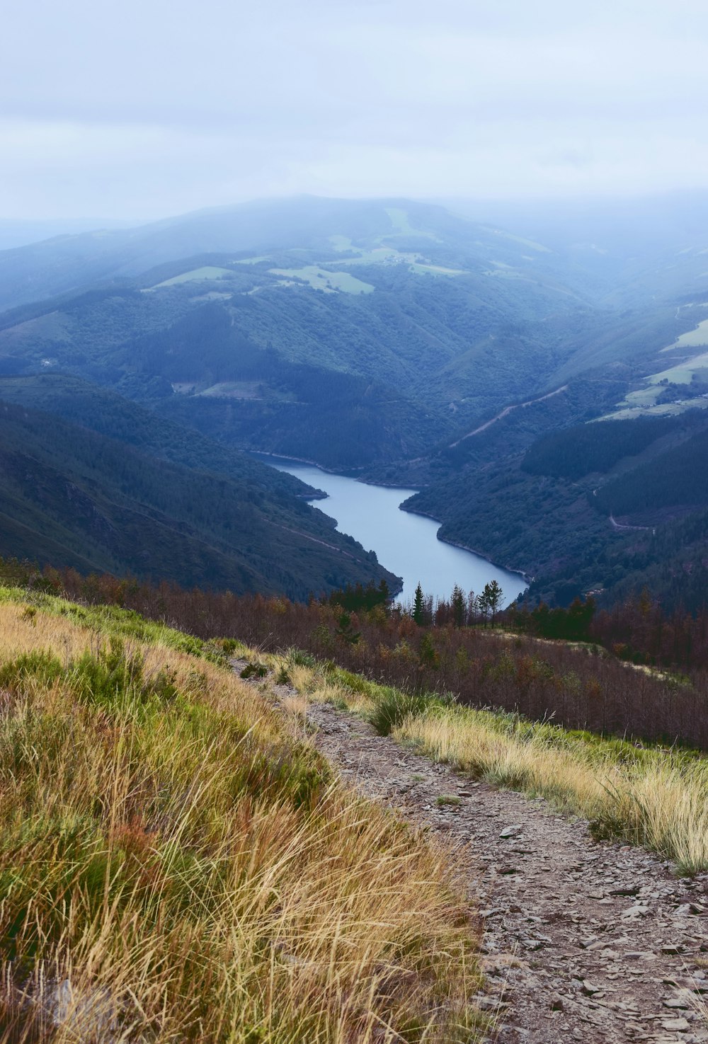 a view of a valley with a lake in the distance