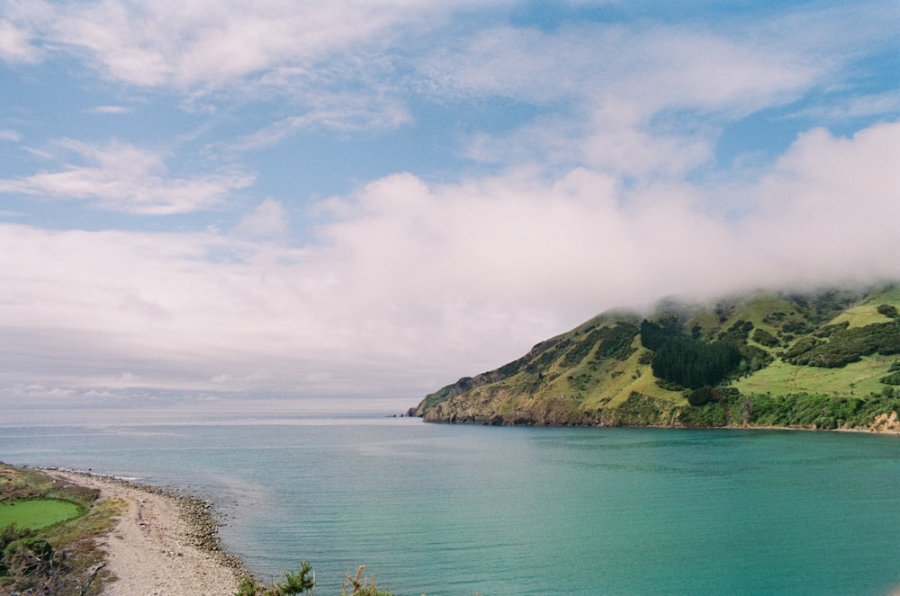 a large body of water surrounded by a lush green hillside