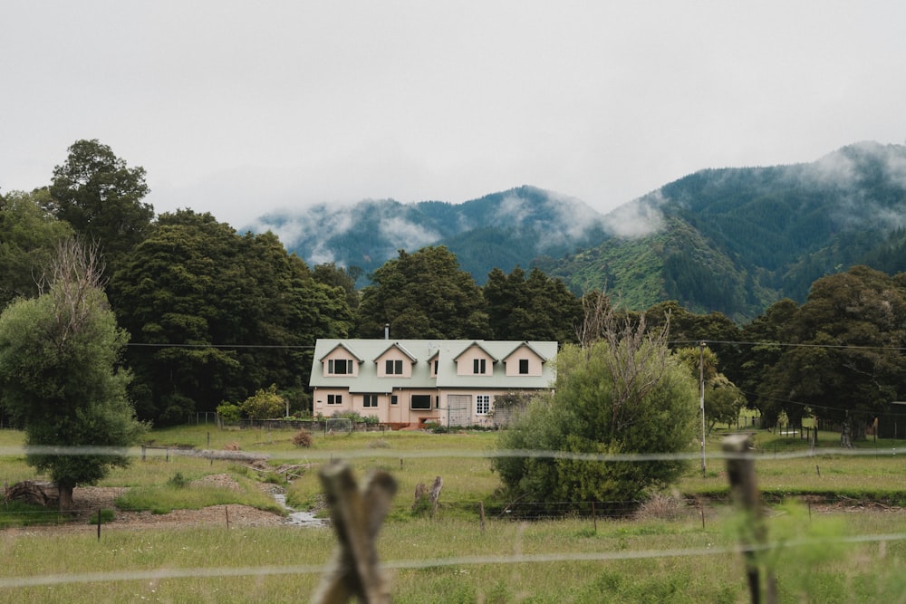 a house in the middle of a field with mountains in the background