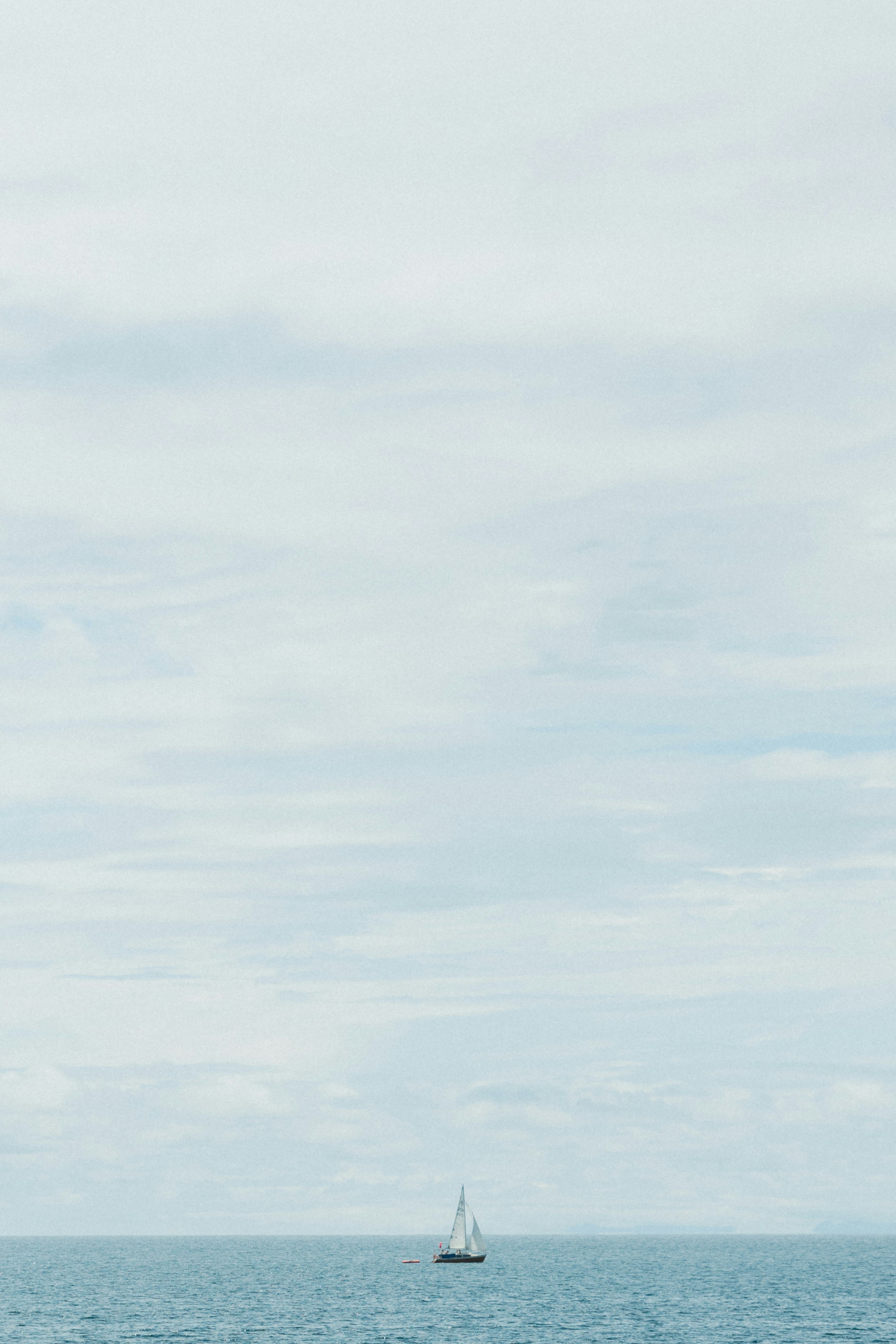 a sailboat in the ocean on a cloudy day