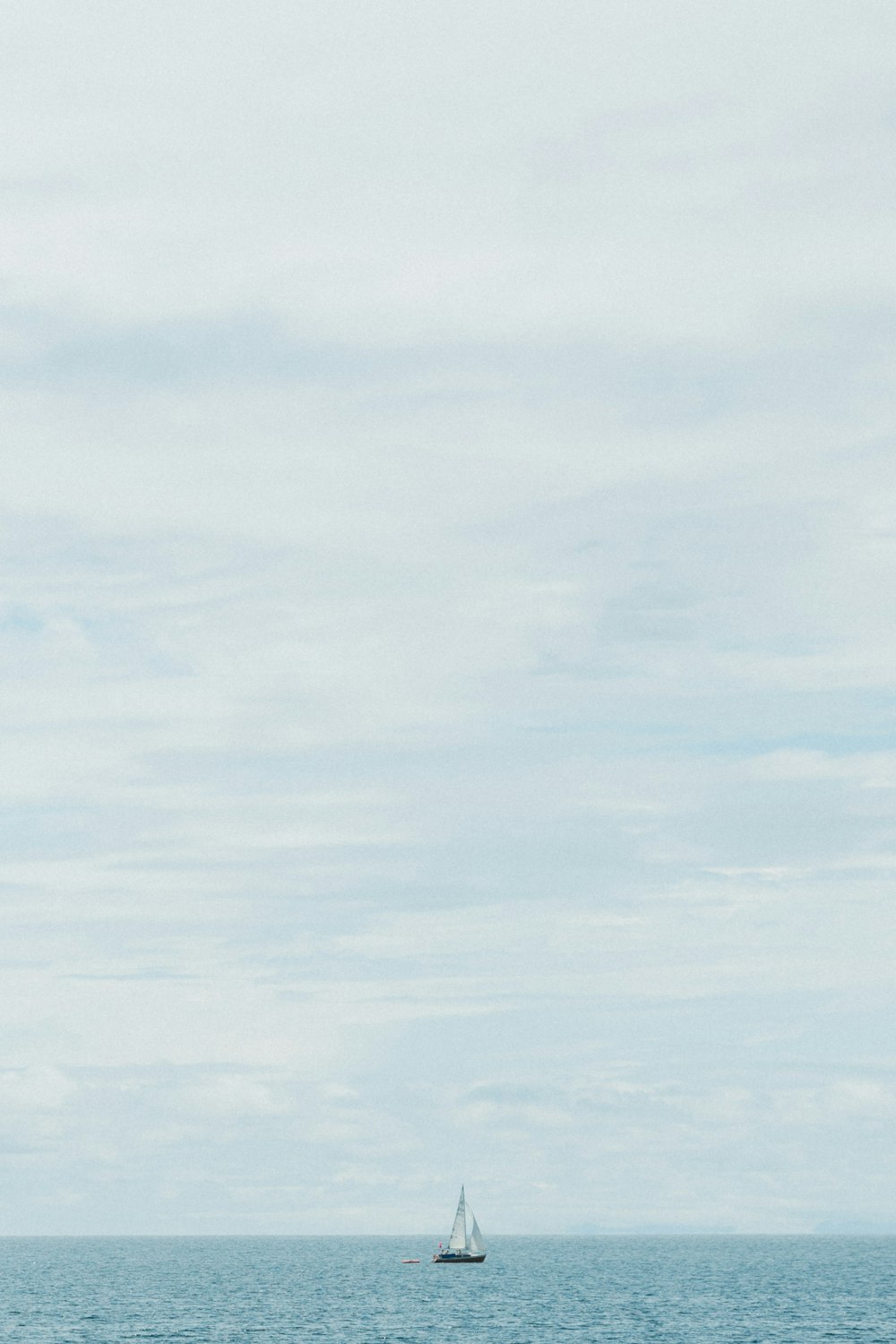 a sailboat in the ocean on a cloudy day