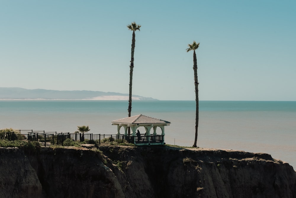 a gazebo sitting on top of a cliff next to the ocean