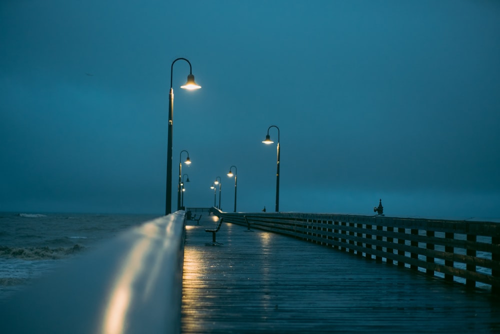 a person sitting on a bench on a pier at night