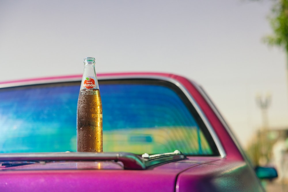 a bottle of beer sitting on top of a purple car