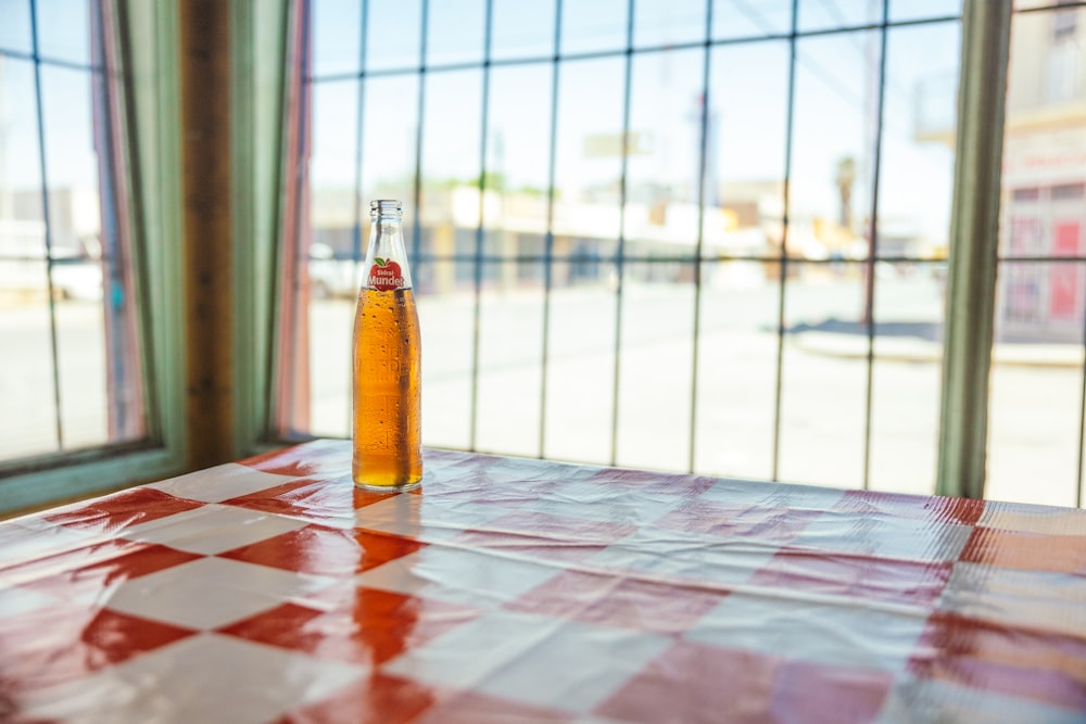 a bottle of beer sitting on top of a red and white checkered table