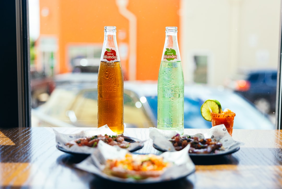 two bottles of soda and a plate of food on a table,
