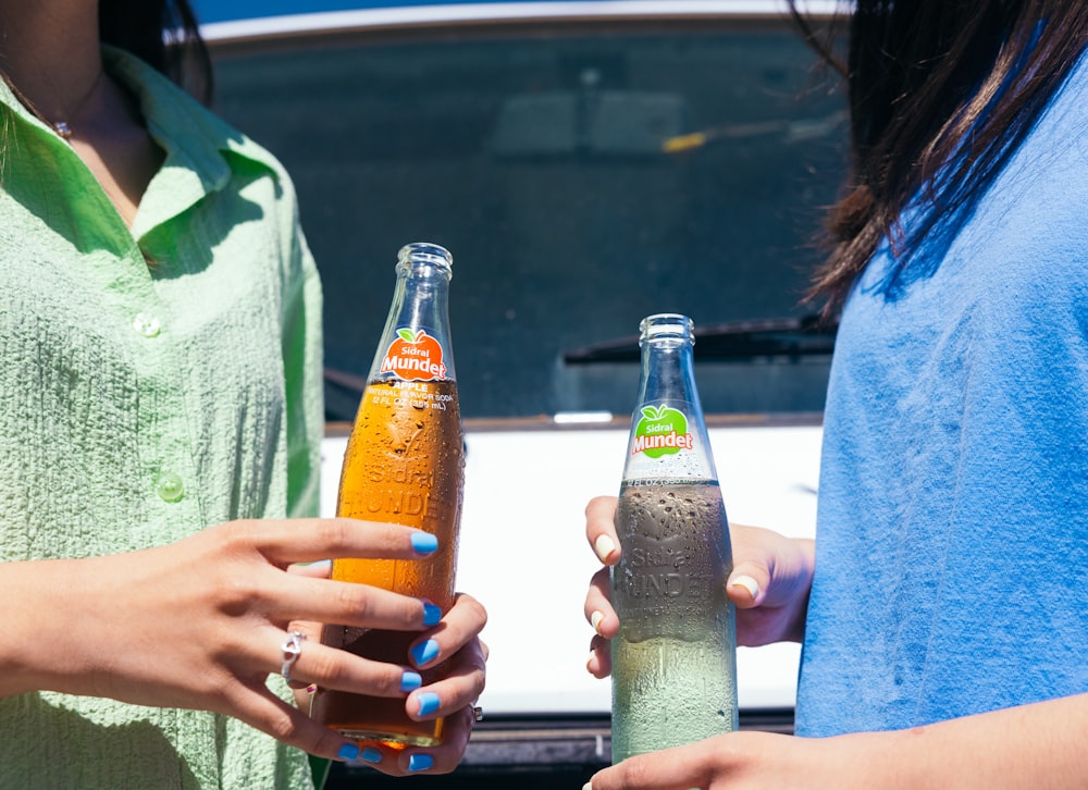 two women standing next to each other holding beer bottles